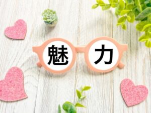 ピンクの丸メガネのレンズに魅力と書かれた文字とハートや観葉植物