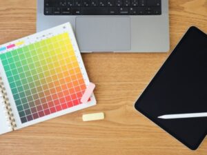 デスクの上に置かれたカラーチャートのノートとパソコンとタブレット