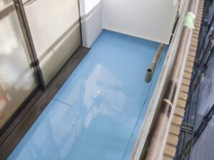 バルコニーの床面に水色の防水塗料が塗られた防水工事完了後の仕上がり写真